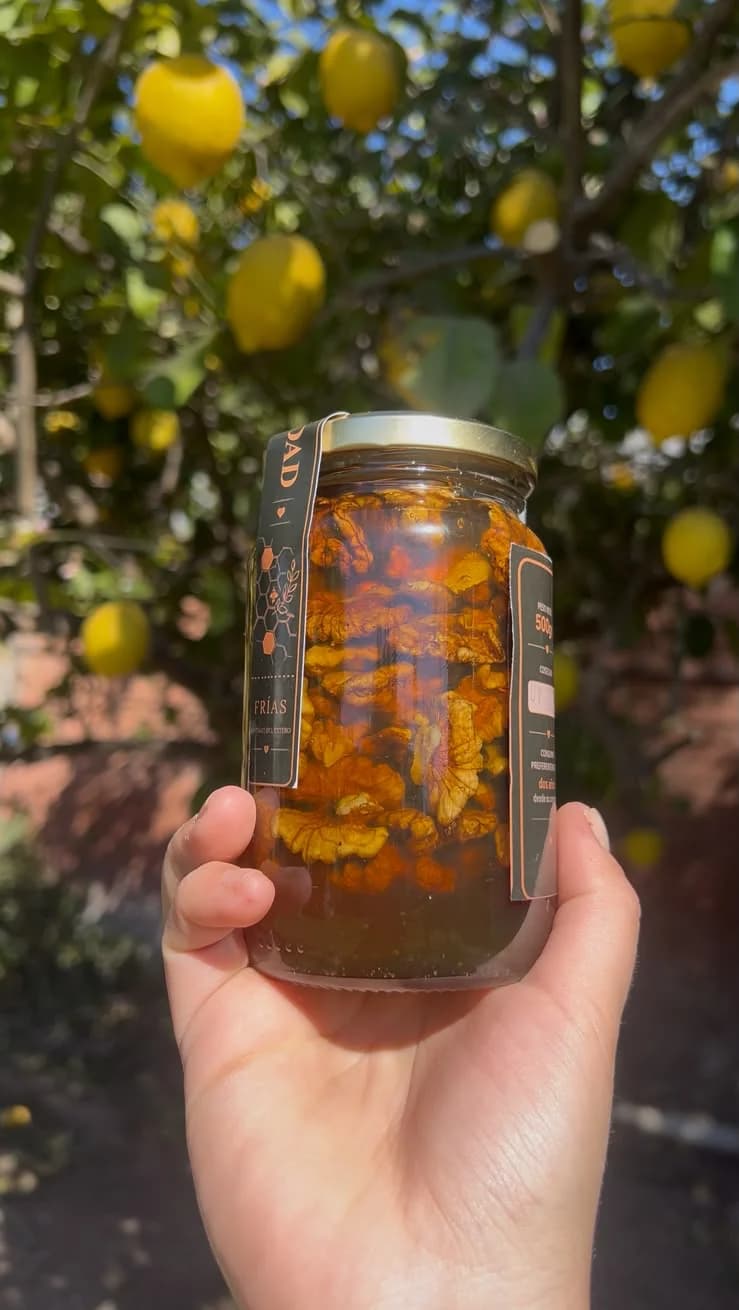 Frasco de Miel del Sol con nueces visto de costado, mostrando las nueces dentro de la miel
